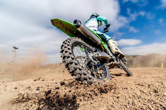 250cc dirt bike rider kicking up dirt on an off-road trail under a blue sky