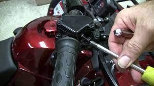 Hand adjusting ATV throttle limiter with screwdriver on youth four-wheeler handlebar
