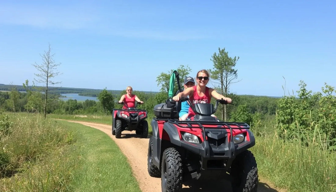 Two people riding red ATVs on a dirt trail through scenic countryside with green trees and lake in background