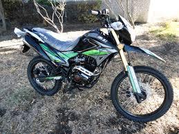 Black and green dual sport motorcycle parked on grass, front view, fuel injected model