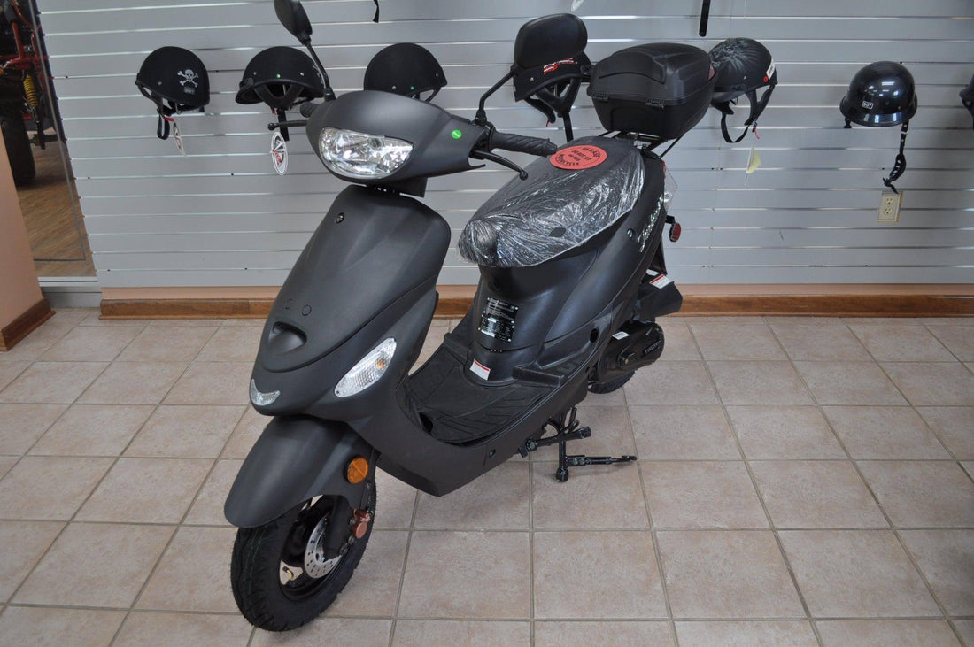 Black 50cc gas scooter on showroom floor with helmets displayed on wall