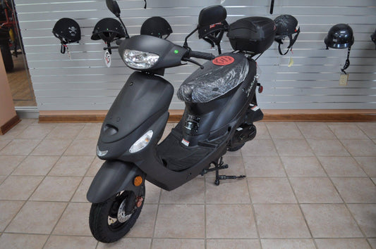 Black 50cc gas scooter on showroom floor with helmets displayed on wall