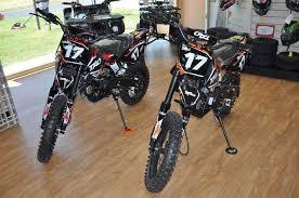 Gas-powered youth dirt bikes with number 17 decals displayed indoors on wood flooring