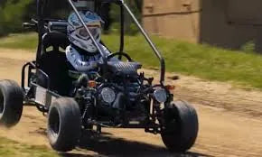 Person driving off-road go-kart on dirt track outdoors