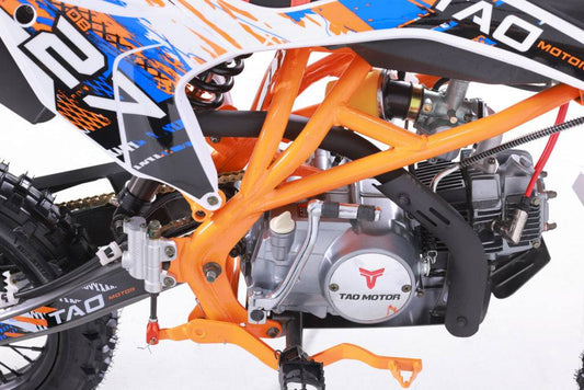 Close-up of 125cc youth dirt bike engine, orange frame, off-road tires, and sporty graphics