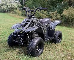 Black kids ATV with spider web graphics parked on grass outdoors