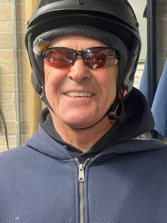 Man wearing a properly fitted motor scooter helmet, sunglasses, and a hoodie indoors