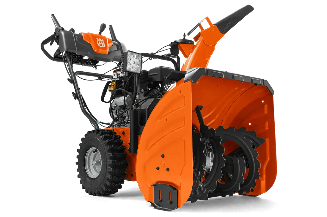 Orange two-stage snow blower with rugged tires and front auger visible against plain background