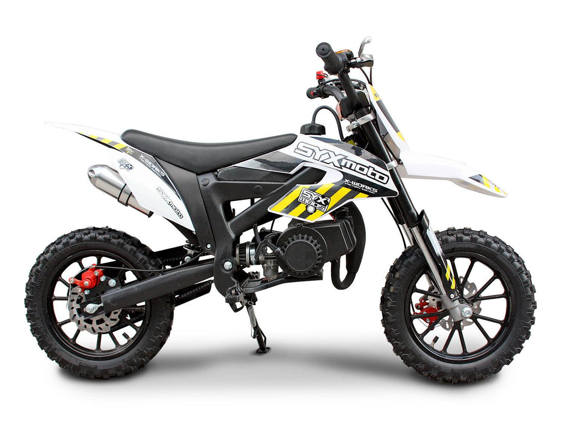 White 50cc kids dirt bike with off-road tires, black seat, and yellow graphics, side view