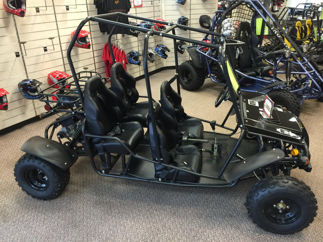 Four-seat black go-kart for kids and teens in Q9 PowerSports USA showroom with helmets and gear.