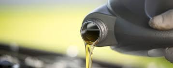 Pouring two-stroke engine oil from bottle, ideal for ATVs, dirt bikes, and scooters