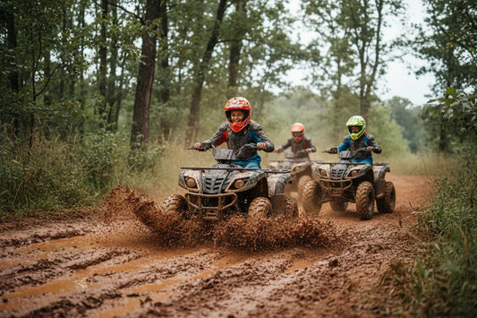 Kids riding ATVs through muddy off-road trail in forest, wearing helmets and gear