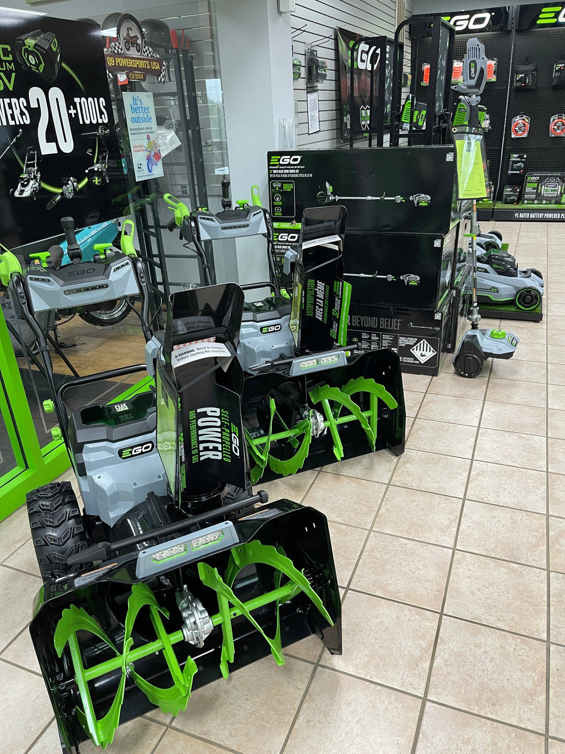 Electric lawn and garden equipment, snow blowers, and power tools on display in a showroom