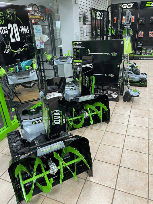 Electric lawn and garden equipment, snow blowers, and power tools on display in a showroom