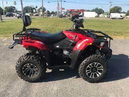 Red all-terrain ATV with rugged tires parked on pavement outdoors