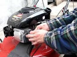 Person repairing a lawn mower engine outdoors, small engine maintenance service