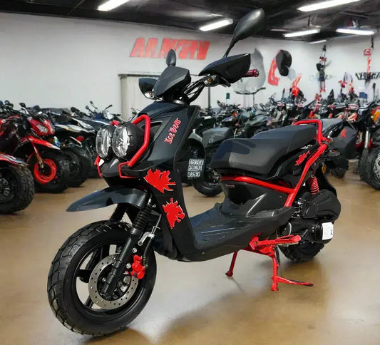 Black and red scooter with dual headlights on showroom floor, surrounded by ATVs and dirt bikes.