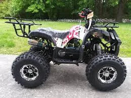 Black and white youth ATV with rugged tires parked outdoors on pavement