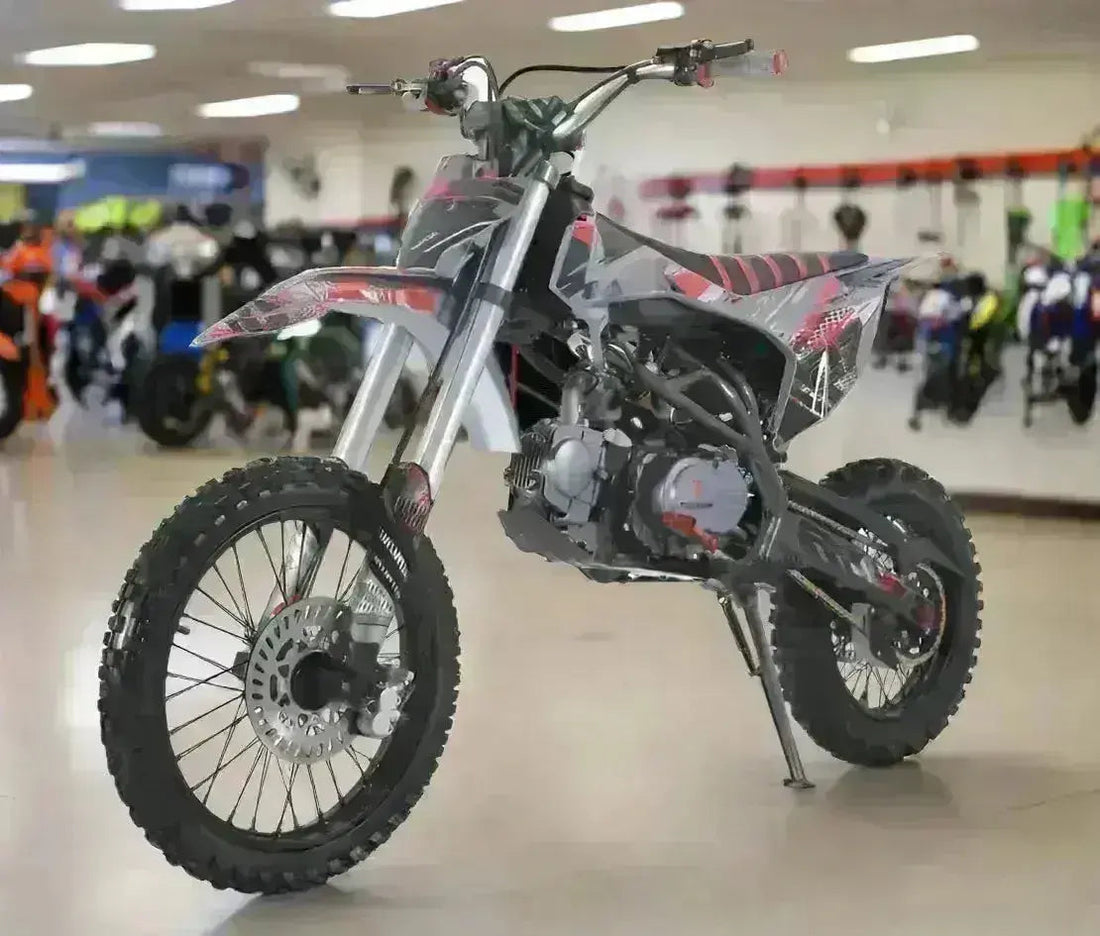 125cc youth dirt bike with knobby tires and black-red graphic design in showroom