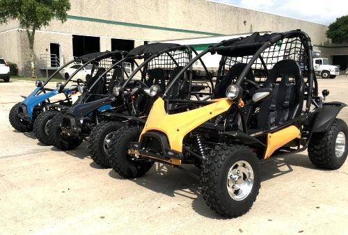 Row of all-terrain go-karts with rugged tires parked outdoors on concrete lot