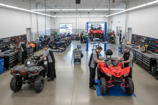 Technicians servicing ATVs and scooters in a clean, organized powersports service center