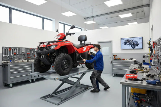 Technician servicing a red ATV in a clean workshop with tools and equipment.