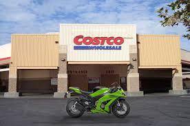 Green sport motorcycle parked in front of a Costco Wholesale store, powersports vehicle on display.