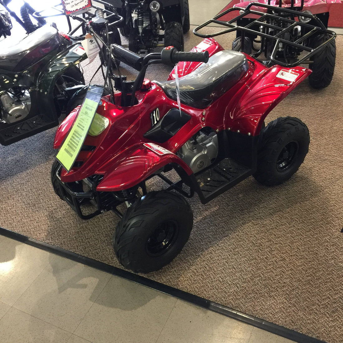 Red youth ATV for beginners displayed indoors with safety features and off-road tires