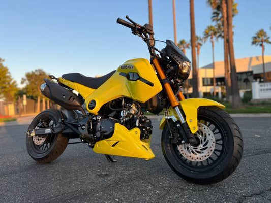 Yellow Fuerza 125cc street motorcycle parked outdoors, sporty design, palm trees in background