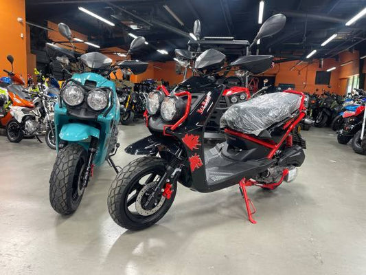 Two 150cc scooters in teal and black colors on showroom floor, double headlights visible