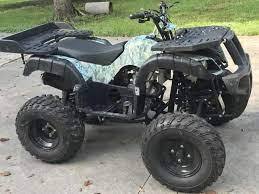 Camo utility ATV with rugged tires parked on pavement, suitable for off-road outdoor use