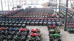Large warehouse filled with rows of ATVs and dirt bikes ready for distribution