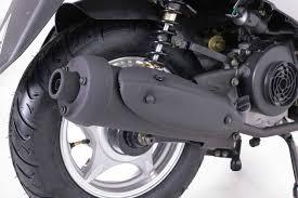 Close-up of a motor scooter rear wheel, tire, exhaust pipe, and suspension on white background