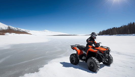 Rider on orange ATV driving across a frozen lake with snow-covered mountains and pine trees