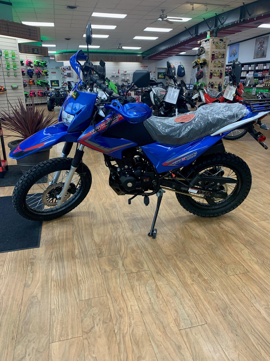 Blue 250cc dual sport motorcycle on showroom floor, off-road tires, and upright handlebars