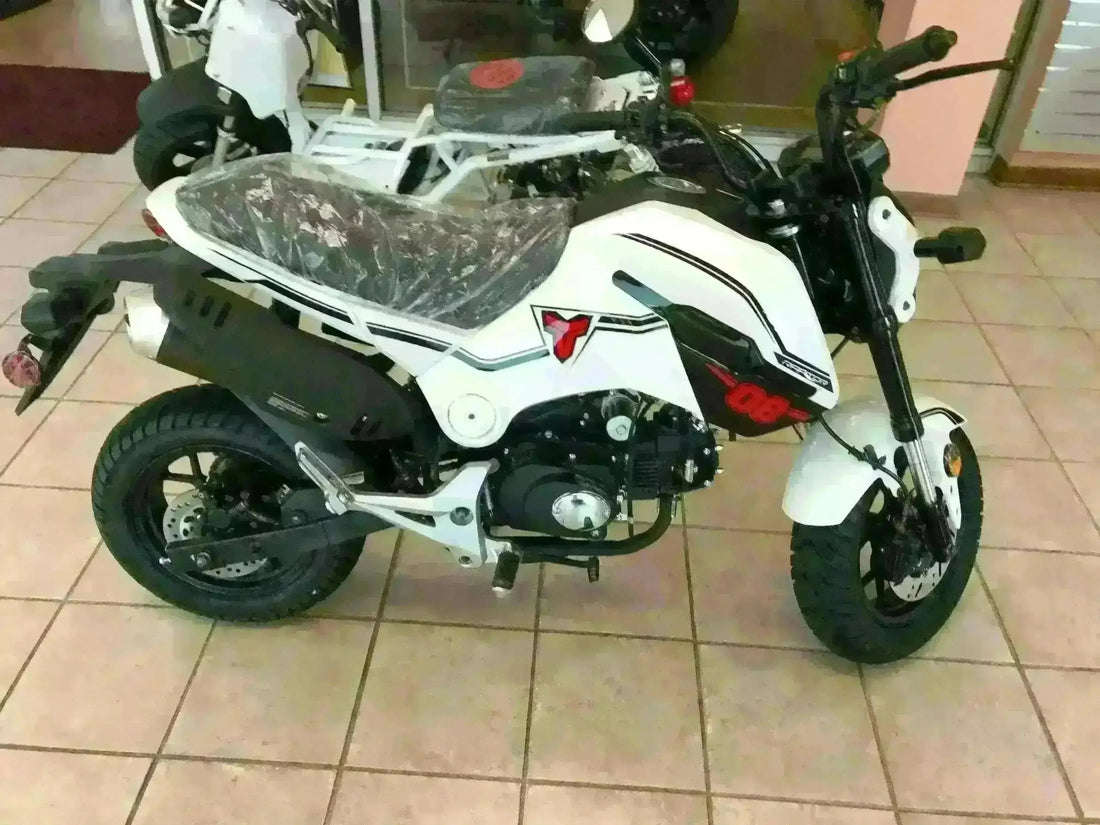 White 125cc mini motorcycle with black accents displayed indoors on a tiled floor