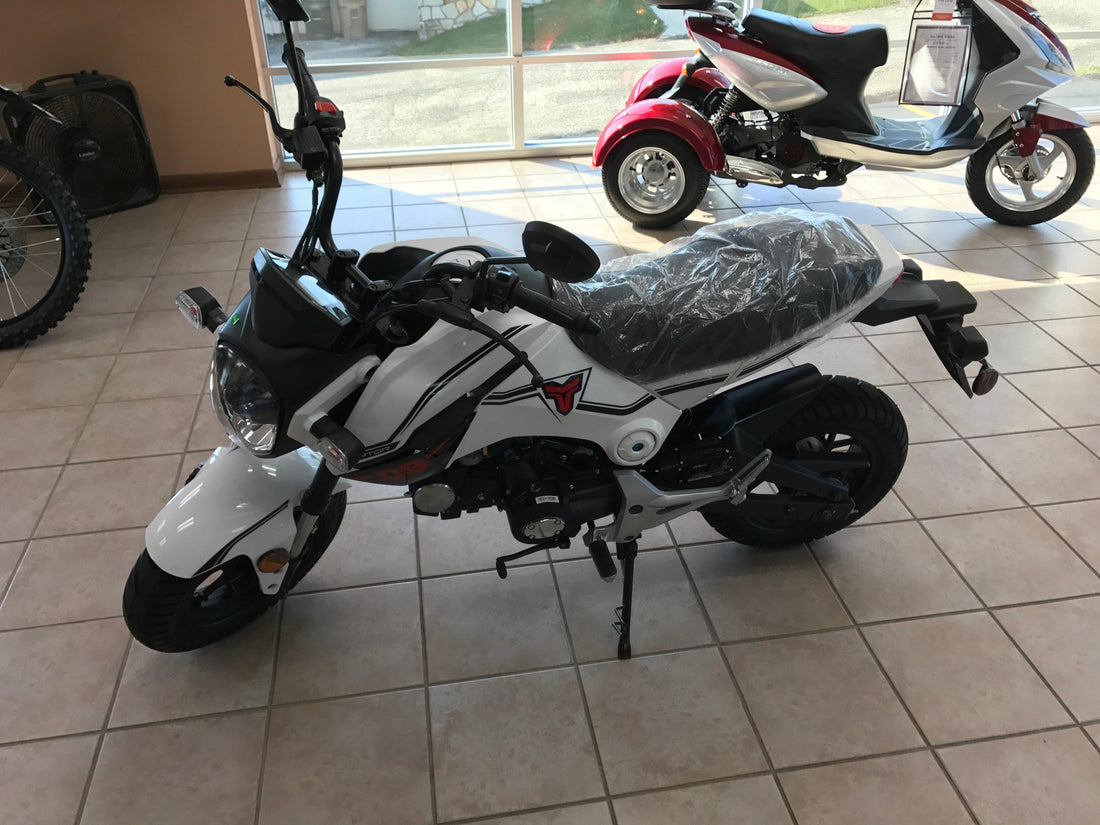 White 125cc street motorcycle for beginners displayed indoors with scooters in background