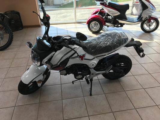 White 125cc street motorcycle for beginners displayed indoors with scooters in background