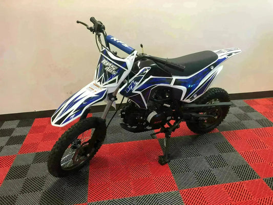 Blue and white RPS 110cc dirt bike with knobby tires on red and gray checkered floor