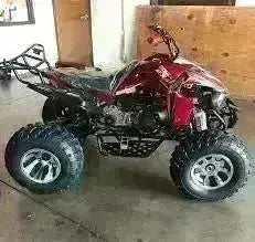 Red 200cc automatic sports ATV with rugged tires parked indoors