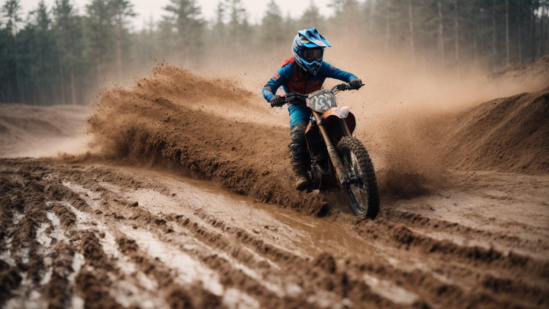 Person riding a dirt bike through muddy off-road trail, wearing blue gear and helmet