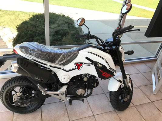 White 125cc mini bike with black trim and red graphics on showroom floor