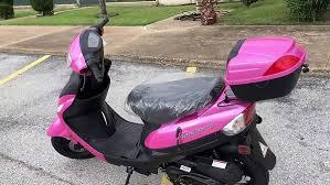 Pink 50cc entry-level scooter parked in an outdoor lot, ideal for beginners.