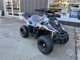 Entry-level kids gas ATV with sporty graphics parked outside showroom