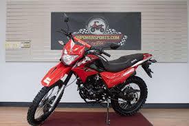 Red dual sport motorcycle parked indoors with off-road tires and modern body design