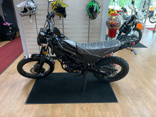 Black 250cc enduro dirt bike for adults on showroom floor, helmets and gumball machine nearby