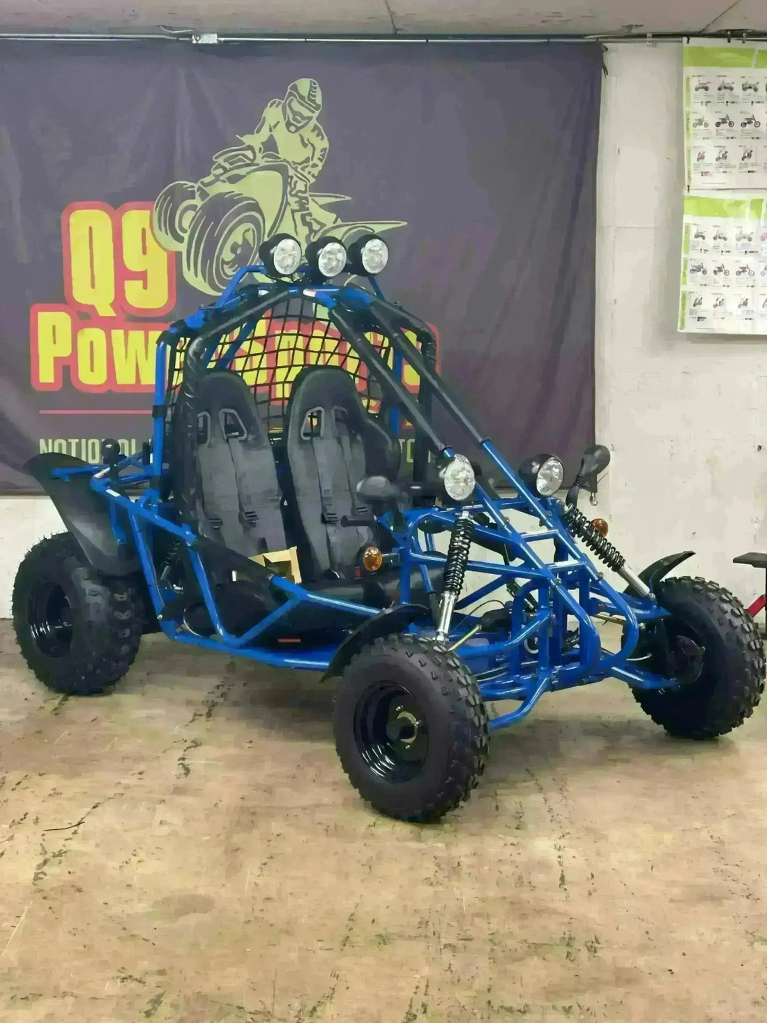 Blue 200cc double seat go-kart with off-road tires and front lights in indoor showroom