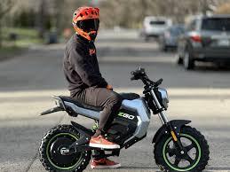 Rider with red helmet on EGO Power 56V electric mini bike parked on suburban street