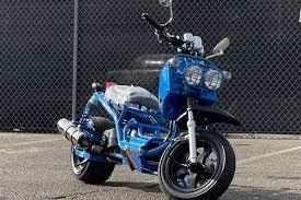Blue Maddog 50cc scooter with dual headlights parked outdoors by chain-link fence