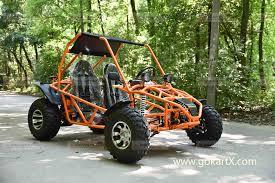 Orange off-road go-kart parked on a forest road with rugged tires and two seats.